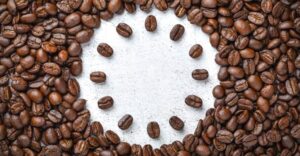 Roda de sabores café - Grãos de café dispostos em círculo sobre superfície clara, formando o contorno de uma roda de sabores.