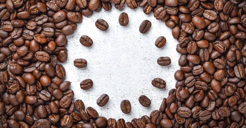 Roda de sabores café - Grãos de café dispostos em círculo sobre superfície clara, formando o contorno de uma roda de sabores.