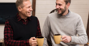 Presente para pai que ama café - Pai e filho sorrindo enquanto compartilham uma bebida quente em canecas, simbolizando momentos de conexão e carinho entre gerações.