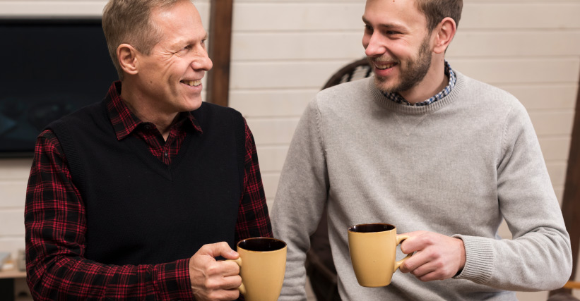Presente para pai que ama café - Pai e filho sorrindo enquanto compartilham uma bebida quente em canecas, simbolizando momentos de conexão e carinho entre gerações.