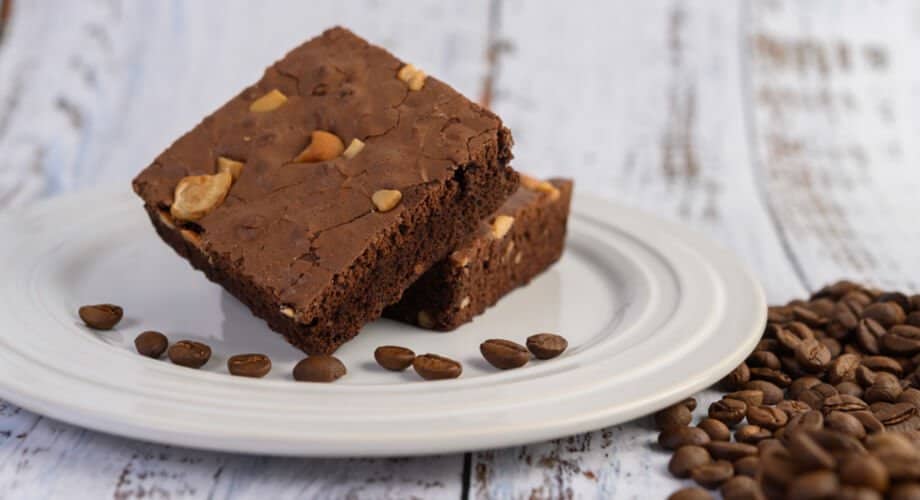 brownie de café - Foto com um brownie de café sobre um pires e alguns grãos de café.